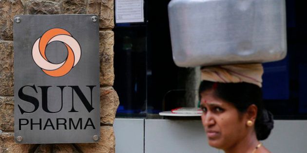 An Indian woman carries a water vessel as she walks past the office of Sun Pharmaceutical in Mumbai, India, Monday, April 7, 2014. The Sun Pharmaceutical Industries is buying troubled generic drugmaker Ranbaxy Laboratories in a $4 billion all-stock transaction, the companies said Monday. (AP Photo/Rafiq Maqbool)