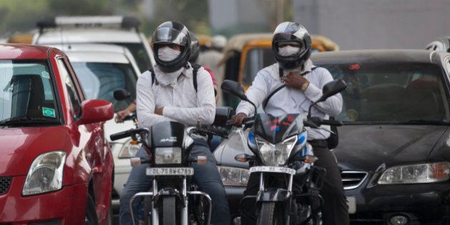Motorists cover their faces to protect themselves from air pollution in New Delhi, India, Tuesday, June 16, 2015. Never mind lowering the rate of death from air pollution in India and China. Just keeping those rates steady will demand urgent action to clear the skies, according to a new report published Tuesday. (AP Photo/Tsering Topgyal)
