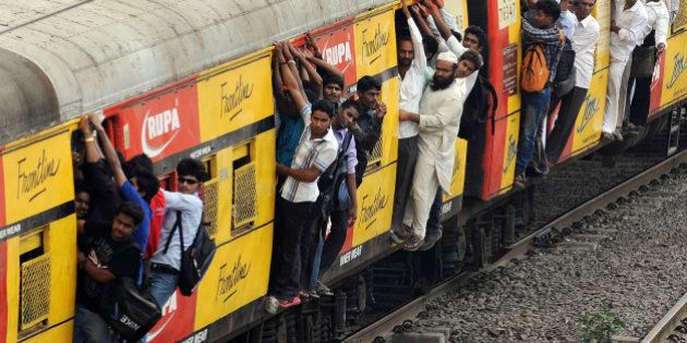 Commuters hang onto an overcrowded suburbun railway train on the Central Railway (CR) line in Mumbai on April 19, 2012. Three people were killed and around 14 were injured when they fell off a moving suburbun train on the CR line. Thousands of commuters in Mumbai had a harrowing time as services on the Central Railway line were thrown out of gear following a fire in a signal cabin between two suburbun railway stations on Tuesday night causing heavy damage to signalling gears. Mumbai's suburban trains or 'locals' carry an estimated seven million people every day and are a lifeline in an overcrowded city with traffic-clogged, potholed roads. Train doors are normally open to the elements to combat high temperatures and humidity, with many travellers also hanging out of carriages or perching between them. AFP PHOTO/Indranil MUKHERJEE (Photo credit should read INDRANIL MUKHERJEE/AFP/Getty Images)