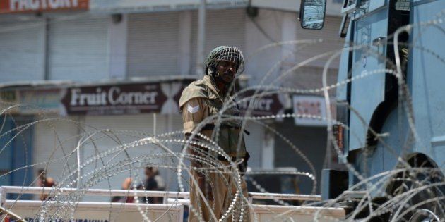 An Indian paramilitary trooper stands guard in between shuttered shops and barbed wire in Srinagar on June 17, 2015 during a one-day strike called by seperatist groups against a recent spate of mysterious killings in Indian-administered Kashmir. Six former rebels and seperatist activists have been killed in Sopore area of the disputed region during the last three weeks. AFP PHOTO/Tauseef MUSTAFA (Photo credit should read TAUSEEF MUSTAFA/AFP/Getty Images)