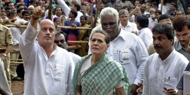 Maharashtra Congress President Gurudas Kamat, left, points towards the landslide site as Congress party President Sonia Gandhi, center, looks on at Saki Naka, a suburb of Bombay, India, Saturday, Aug. 13, 2005, where a landslide caused by rainwater killed 45 people on July 26. Gandhi is on a visit to the city that is battling waterborne diseases which has killed at least 66 people, after the city was crippled by rainwater floods. (AP Photo/Rajesh Nirgude)