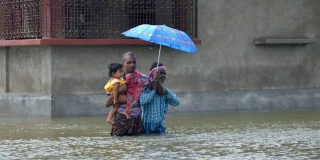 In this photograph taken on August 1, 2015, Indian villagers wade through floodwaters in Bherampur Block, Murshidabad District, some 220kms north of Kolkata as the remnants of Cyclone Komen carrying heavy monsoon rains cross the eastern Indian state of West Bengal. Scores have perished in India, Nepal, Pakistan and Vietnam following floods and landslides triggered by heavy seasonal rains. AFP PHOTO/STR (Photo credit should read STRDEL/AFP/Getty Images)