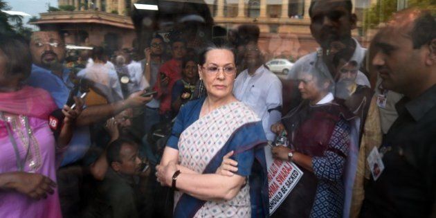 Congress President Sonia Gandhi (C) waits for Vice President Rahul Gandhi and former Prime Minister Manmohan Singh to address the media after a protest by Congress Party Members of Parliament at the Mahatma Gandhi statue outside Parliament house in New Delhi on August 4, 2015. Congress MPs protested outside Parliament, including former Prime Minister Manmohan Singh, Congress vice-president Rahul Gandhi and other senior party leaders who raised slogans against Prime Minister Narendra Modi and the NDA government following the suspension of 25 of their MPs, and demanded the resignation of Foreign Minister Sushma Swaraj. AFP PHOTO/ PRAKASH SINGH (Photo credit should read PRAKASH SINGH/AFP/Getty Images)