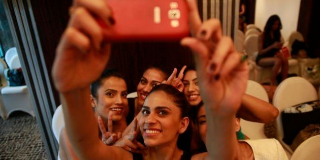 An Indian model takes a photograph of herself with other models on a mobile phone as they wait to participate in an audition for the upcoming Lakme Fashion Week, in Mumbai, India, Thursday, July 3, 2014. The event is scheduled to begin August 20, 2014 in Mumbai. (AP Photo/Rafiq Maqbool)