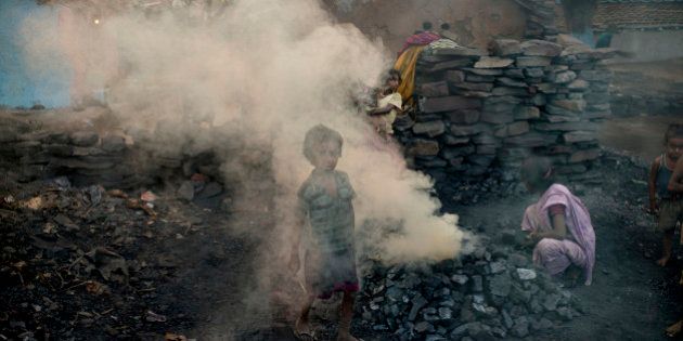 JHARIA, JHARKAND, INDIA - 2014/10/24: A child walks through a cloud of smoke in a village located between one the coal mines. Methane and other toxic gases spew from the open wounds in the crust near coal mines in Jharia. Jharia in India's eastern Jharkand state is literally in flames. This is due to the open cast coal mining that takes place in the area. For more than 90 years, the Jharian coal mines have been alight with coal mining villages of around seven hundred thousand people settling in. Most of the mining is done with open cast as the price to mine is relatively lower to produce the profits. However, open cast mining does have its disadvantages including the release of toxic chemicals into our atmosphere. Everywhere you look, there will be coal to mine. And so villagers in Jharia often go out with their own shovels to mine whatever coal there is in the ground to support their families after selling the coal at the market center. The open pits of coal on the other hand, often catch fire due to careless cigarette bud tipping or due to lightning strikes in the area and will burn for years to come; spewing toxic and hazardous chemicals into the Earth's atmosphere. About 1.4 billion tonnes of carbon dioxide gets pumped into the atmosphere and could even be considered as the 4th most polluting area of India. Life however, is something that most will fight for, and if destroying the environment means feeding their families; workers will continue to run outside with their shovels and dig up all the coal they can find to survive. (Photo by Jonas Gratzer/LightRocket via Getty Images)