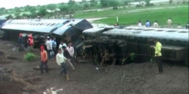 In this image made from video, people gather by the scene where two trains derailed in Harda in Madhya Pradesh state, India, Wednesday, Aug. 5, 2015. Two passenger trains derailed over a bridge in central India while crossing a track that was flooded by heavy monsoon rains, killing at a number of people, officials said Wednesday. (Photo via AP Video)