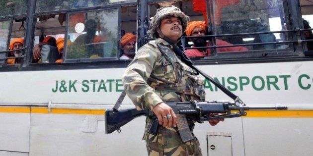 JAMMU, INDIA - AUGUST 5: A CRPF soldier guards the bus carrying passengers of the Amarnath Yatra which was halted due to the terrorist attack on BSF convoy at Jammu-Srinagar national highway on August 5, 2015 in Udhampur near Jammu, India. A terrorist, identified as Mohammed Naved Yakub, son of Mohammed Yakub from Faisalabad in Pakistan and belong to Lashkar-e-Taiba terror group, was nabbed by the Village Defence Committee members after the attack. While his fellow terrorist identified as Noman alias Momin was killed in the gun fight. Two BSF soldiers also lost their life. (Photo by Nitin Kanotra/Hindustan Times via Getty Images)