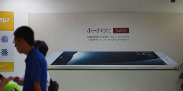 Customers wait near an advertisement for the Xiaomi Note mobile phone at a Xiaomi service center in Beijing on August 5, 2015. Chinese company Xiaomi was the largest smartphone vendor in China based on shipments with a 15.9 percent market share in the second quarter of 2015, according to Canalys. Telecom equipment maker Huawei was close behind at 15.7 percent, it said, followed by Apple, South Korea's Samsung and Chinese firm Vivo. AFP PHOTO / GREG BAKER (Photo credit should read GREG BAKER/AFP/Getty Images)
