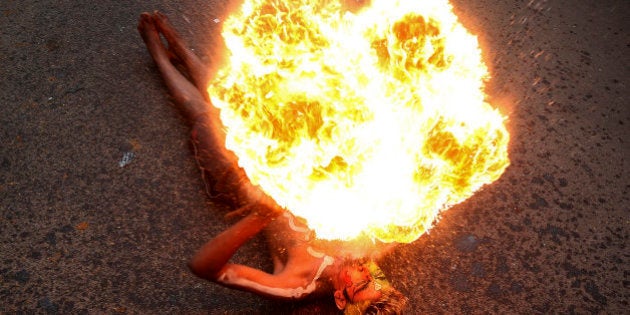 An Indian artist performs with fire during a procession as part