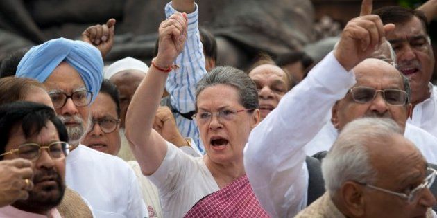 Former Indian Prime Minister Manmohan Singh, left in blue turban, watches as Indiaâs opposition Congress party president Sonia Gandhi, center, and other lawmakers shout slogans against the government during a protest in the parliament premises in New Delhi, India, Wednesday, Aug. 5, 2015. The opposition has been demanding that two leaders of the ruling Bharatiya Janata Party resign for allegedly helping a former Indian cricket official facing investigation for financial irregularities. (AP Photo/Manish Swarup)