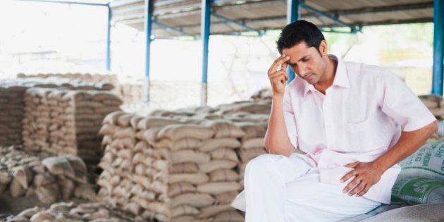 Stressed man sitting on a stack of sacks in warehouse, Anaj Mandi, Sohna, Gurgaon, Haryana, India