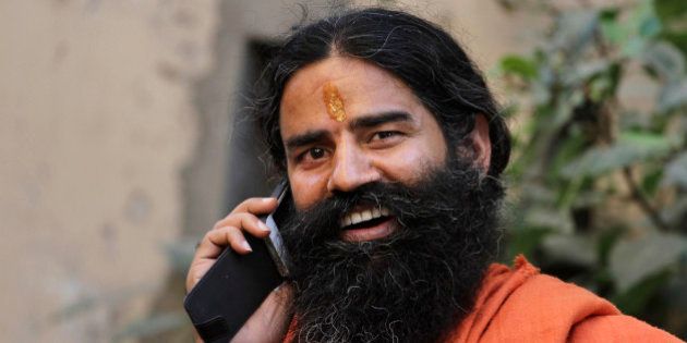 Indian yoga guru Baba Ramdev talks on a mobile phone, as he leaves after a press conference in Ahmadabad, India, Monday, Oct. 29, 2012. (AP Photo/Ajit Solanki)