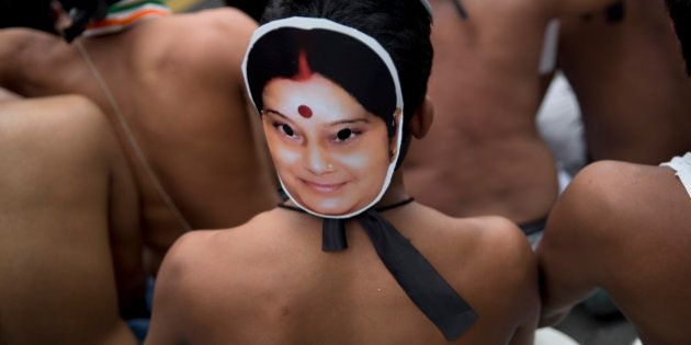 A bare chest protester of India's opposition Congress party's youth wing wears a mask with portrait of Foreign Minister Sushma Swaraj as he participates in a protest in New Delhi, India, Thursday, Aug. 6, 2015. The protesters demonstrated against the decision of Lok Sabha, or the lower house speaker, Sumitra Mahajan of the ruling Bharatiya Janata Party (BJP), who suspended 25 Congress party members from the Lok Sabha. The opposition also continued to demand the resignation of the two leaders of BJP for allegedly helping a former Indian cricket official facing investigation for financial irregularities. (AP Photo/Tsering Topgyal)