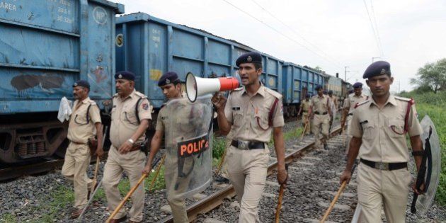 Indian police patrol railway tracks damaged by rioters on the outskirts of Ahmedabad on August 26, 2015. Thousands of Indian paramilitary troops have been sent to the western state of Gujarat to contain violence that broke out after an estimated half a million of the Patidar or Patel caste rallied to demand favourable treatment. Authorities have imposed a curfew in parts of Ahmedabad and five other cities and towns after stone-throwing members torched cars, buses and police stations. AFP PHOTO / Sam PANTHAKY (Photo credit should read SAM PANTHAKY/AFP/Getty Images)