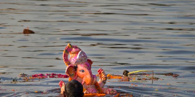 An Indian Hindu devotee immerses an idol of the elephant-headed Hindu God Ganesh into the river Yamuna, in New Delhi, India, Monday, Sept. 8, 2014. Every year millions of devout Hindus immerse Ganesh idols into oceans and rivers in the ten-day long Ganesh Chaturthi festival that celebrates the birth of Ganesh. (AP Photo /Manish Swarup)