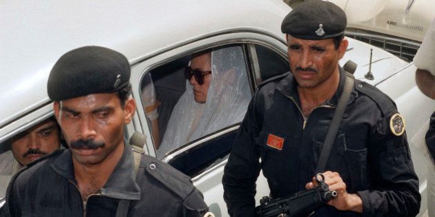 Crack commandos called black cat security guards with automatic weapons walk beside the car carrying Sonia Gandhi (wearing sunglasses) in New Delhi, India, May 24, 1991. Sonia Gandhi rode in the car behind her husband?s body contrary to Hindu tradition, in which widows do not take part in the funeral procession. (AP Photo/Michel Euler)