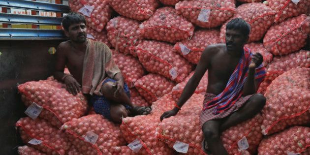 Indian workers rest on onion bags while loading them into a truck at a wholesale market in Hyderabad, India, Tuesday, Aug.25, 2015. The prices of onion, a staple food of the Indian middle class, have been soaring in the past weeks leading to protests. (AP Photo/Mahesh Kumar A.)