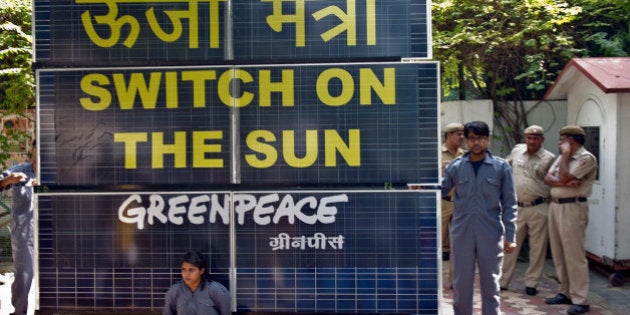 Indian policemen look on as Greenpeace activists chained to a bank of solar panels block the entry to the residence of Delhi's Power Minister Haroon Yusuf in New Delhi on May 15, 2013. Greenpeace activists demanded that Delhi Government should take steps to improve its performance on the use of renewable source of energy to deal with capital's power crisis. AFP PHOTO/Prakash SINGH (Photo credit should read PRAKASH SINGH/AFP/Getty Images)