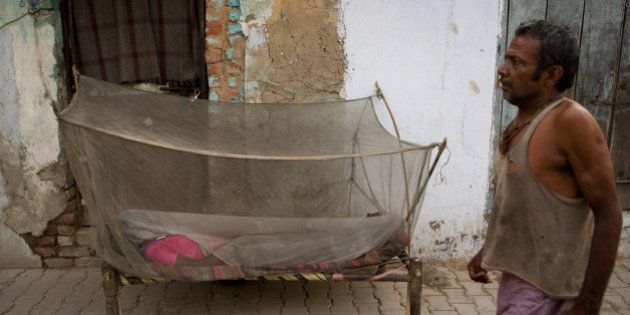 An Indian labourer walks past a women sleeping under a mosquito net in New Delhi early June 4, 2012. Dengue fever caused by mosquito bites is a seasonal, sometimes fatal viral disease transmitted by the Aedes mosquito, which bites during the day. AFP PHOTO/ ANDREW CABALLERO-REYNOLDS (Photo credit should read Andrew Caballero-Reynolds/AFP/GettyImages)