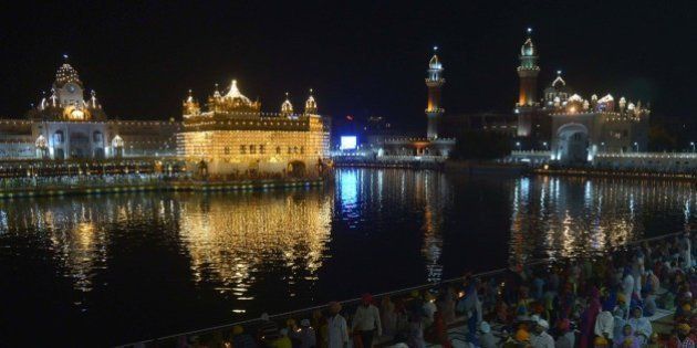 Indian Sikh devotees watch a fireworks display at the illuminated Sikh shrine Golden Temple in Amritsar on September 14, 2015. The event took place for the 411th anniversary of the installation of the Guru Granth Sahib, the holy book of the Sikh religion. AFP PHOTO/ NARINDER NANU (Photo credit should read NARINDER NANU/AFP/Getty Images)