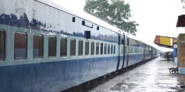blue color coaches of indian train stainding in a station during rain