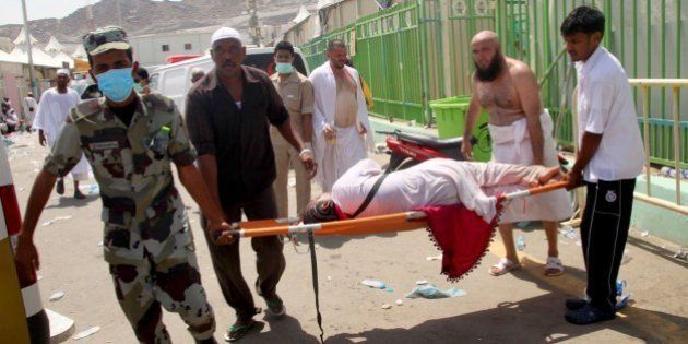 Hajj pilgrims and Saudi emergency personnel carry a woman on a stretcher at the site where at least 450 were killed and hundreds wounded in a stampede in Mina, near the holy city of Mecca, at the annual hajj in Saudi Arabia on September 24, 2015. The stampede, the second deadly accident to strike the pilgrims this year, broke out during the symbolic stoning of the devil ritual, the Saudi civil defence service said. AFP PHOTO / STR (Photo credit should read STR/AFP/Getty Images)