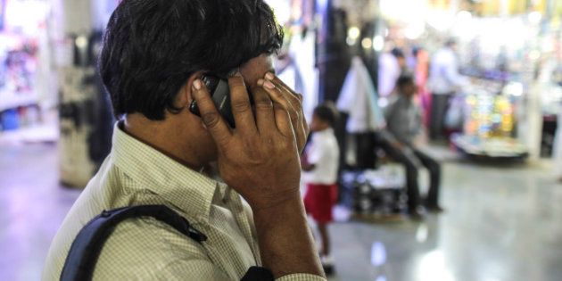 A man reacts while talking on a Karbonn Mobiles India Pvt. phone outside Chhatrapati Shivaji Terminus railway station during the morning rush hour in Mumbai, India, on Thursday, Feb. 26, 2015. The government auction of telecom wireless spectrum starting March 4 is expected to raise as much as $15.6 billion from service providers including those controlled by billionaires Kumar Mangalam Birla, Sunil Mittal and Anil Ambani, according to ICRA Ltd. Photographer: Dhiraj Singh/Bloomberg via Getty Images