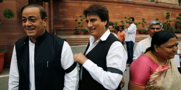 A Congress party lawmaker ties a black band on his colleague's hand during a protest in the Parliament premises in New Delhi, India, Friday, Aug. 7, 2015. The opposition continued their protests Thursday demanding that two leaders of the ruling Bharatiya Janata Party resign for allegedly helping a former Indian cricket official facing investigation for financial irregularities. (AP Photo/Manish Swarup)