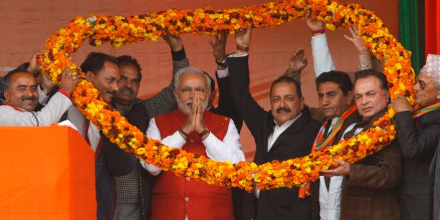 India's ruling Bharatiya Janata Party (BJP) supporters hold a giant floral garland around Prime Minister Narendra Modi during an election campaign rally in Kathua, about 90 kilometers from Jammu, India, Saturday, Dec.13, 2014. The final two phases of the five-phased state elections of Jammu and Kashmir will be held on Dec. 14 and 20. (AP Photo/Channi Anand)