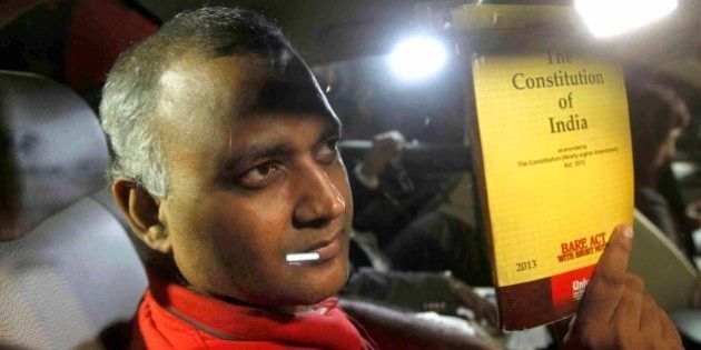 NEW DELHI, INDIA - SEPTEMBER 28: AAP MLA Somnath Bharti shows a book of Constitution of India as he arrives to surrender at the Dwarka North Police Station on September 28, 2015 in New Delhi, India. Somnath Bharti, who has been evading arrest for nearly a week, surrendered before police tonight hours after the Supreme Court ordered him to give up by evening in the domestic violence and attempt to murder case filed by his wife. (Photo by Vipin Kumar/Hindustan Times via Getty Images)