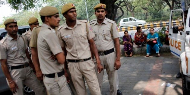 Delhi policemen stand guard as members of All India Democratic Women's Association (AIDWA) sit on a pavement at the end of a protest against the gang rape of two teenage girls, in New Delhi, India, Saturday, May 31, 2014. Police arrested a third suspect and hunted for two others Saturday in the gang rape and slaying of two teenage cousins found hanging from a tree in Katra village, in the northern Indian state of Uttar Pradesh, a case that has prompted national outrage. (AP Photo/Altaf Qadri)