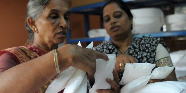 Savitaben Patel, CEO of Self Employed Women's Association (SEWA) and Assistant Project Manager, Nilam Solanki (R) check the quality of low cost sanitary pads made by members at their facility in Ahmedabad on September 3, 2012. Prompted by the widespread suffering of women and girls in rural areas who continue to be plagued by unhygienic old cloth pieces or rags during their menstrual cycle periods, SEWA has began manufacturing low cost sanitary pads with the current production capacity at 2,000 pads per day. The price of each sanitary pad will be about one Indian rupee. AFP PHOTO / Sam PANTHAKY (Photo credit should read SAM PANTHAKY/AFP/GettyImages)