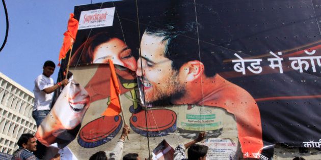 Indian supporters of the Hindu right wing Sanskriti Bachao (Save the Culture) organisation tear down a poster advertising condoms in Bhopal on January 14, 2010. The right wing outfit in central India has ordered shopkeepers to remove lingerie advertisements and mannequins displaying undergarments while condemning condom advertisements as they consider them to be obscene and against traditional Indian values. AFP PHOTO/STR (Photo credit should read STR/AFP/Getty Images)