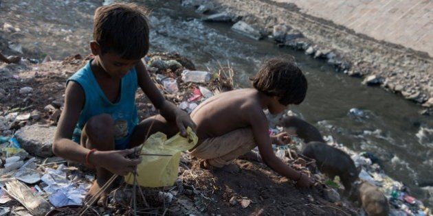 Indian boys Chandan (L), 6, and Badar, 5, sort through waste on the banks of a small polluted tributary flowing into the River Ganges, as they look for bits of scrap metal they can sell for a few rupees in Varanasi on September 16, 2015. The Ganges is heavily polluted with raw sewage, animal and human corpses, and industrial waste entering the waterway, which is considered holy in Hindu-majority India. Millions of children work long hours often in poor conditions in the south Asian giant, where almost a quarter of the 1.2 billion population lives on less than USD 1.25 a day. AFP PHOTO / ALEX OGLE (Photo credit should read Alex Ogle/AFP/Getty Images)