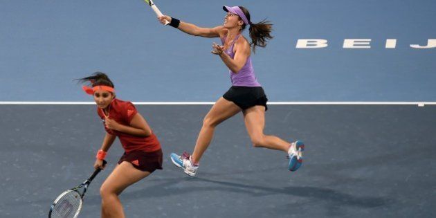 Martina Hingis (top) of Switzerland hits a return as she partners Sania Mirza of India during their second round women's doubles match against Sara Errani and Flavia Pennetta of Italy at the China Open tennis tournament in Beijing on October 7, 2015. AFP PHOTO / GOH CHAI HIN (Photo credit should read GOH CHAI HIN/AFP/Getty Images)