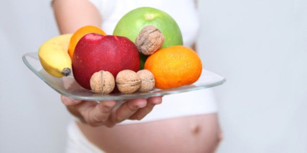 Pregnant woman holding fruits.