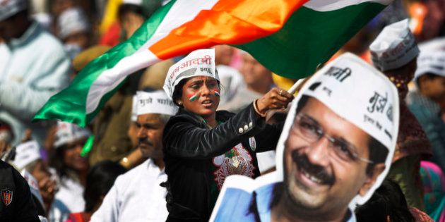 A supporter of Aam Aadmi Party, or Common Man's Party, waves an Indian flag next to a cut-out of party leader Arvind Kejriwal during his swearing-in ceremony as chief minister of Delhi in New Delhi, India, Saturday, Feb. 14, 2015. The AAP, headed by the former tax official who had remade himself into a champion for clean government, won 67 of the 70 seats in recent elections. (AP Photo/Altaf Qadri)