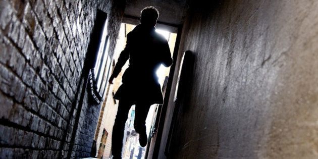A mysterious running man silhouetted in a dark alleyway.