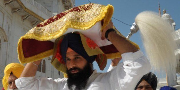 Indian Punjab Revenue Minister Bikram Singh Majithia (C) carries the Guru Granth Sahib (Sikh holy book ) following a religious punishment for altering a Sikh hymn to include the name of Bharatiya Janata Party (BJP) candidate for Amritsar in India's general election Arun Jaitley at the Golden Temple in Amritsar on May 14, 2014. Sikh religious officials ordered Majithia to undertake a period of community service. AFP PHOTO/NARINDER NANU (Photo credit should read NARINDER NANU/AFP/Getty Images)