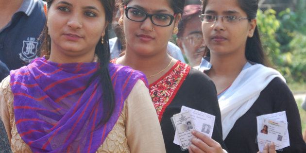 BHAGALAPUR, INDIA - OCTOBER 12: Voters pose with their cards for picture as they wait in a long queue to cast their votes during the first phase of Bihar Assembly polls, at Durgacharan High School on October 12, 2015 in Bhagalpur, India. An estimated 57 per cent of the electorate cast their votes in the first phase of Bihar Assembly elections in 49 constituencies which was violence-free note today. (Photo by Hindustan Times via Getty Images)