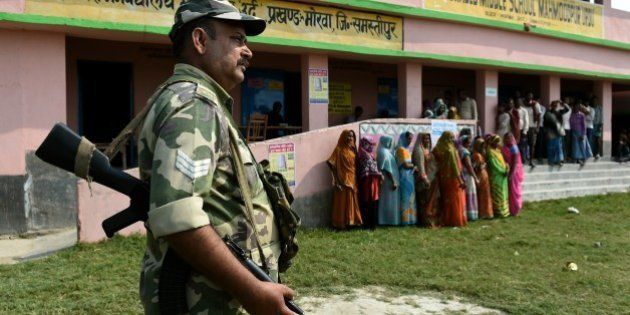 Indian voters queue to cast their ballots as security personnel stand guard at a voting centre in the village of Mahmoodpur in Samstipur district on October 12, 2015. The first of five phases of voting in the state assembly elections in Bihar, one of India's largest and poorest states, begins on October 12. AFP PHOTO / MONEY SHARMA (Photo credit should read MONEY SHARMA/AFP/Getty Images)