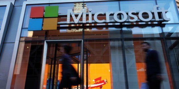 People walk past a Microsoft office in New York on October 6, 2015. Microsoft introduced a pair of big-screen smartphones and a laptop during an event in New York on Tuesday. The company unveiled the Surface Book, a laptop with 13.5-inch detachable touchscreen, the Surface Pro 4 tablet and the Lumia 950 and 950 XL smartphones, which feature displays measuring over 5 inches. The Surface devices launch later this month, while the Lumias arrive in November. AFP PHOTO/JEWEL SAMAD (Photo credit should read JEWEL SAMAD/AFP/Getty Images)