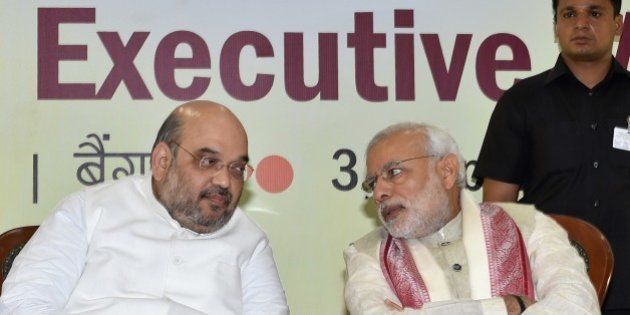Indian Prime Minister Narendra Modi (R) and Bharatiya Janata Party (BJP) National President Amit Shah speak at a BJP National Executive committee meeting in Bangalore on April 3, 2015. AFP PHOTO/Manjunath KIRAN (Photo credit should read MANJUNATH KIRAN/AFP/Getty Images)