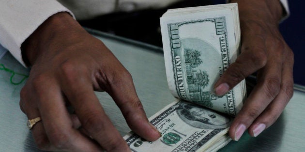 An Indian man counts U.S dollars at a Western Union money transfer center in Ahmadabad, India, Monday, May 21, 2012. The Indian rupee hit a fresh all-time low of 55.03 against the US dollar Monday amid robust demand for the US currency from banks and importers. (AP Photo/Ajit Solanki)