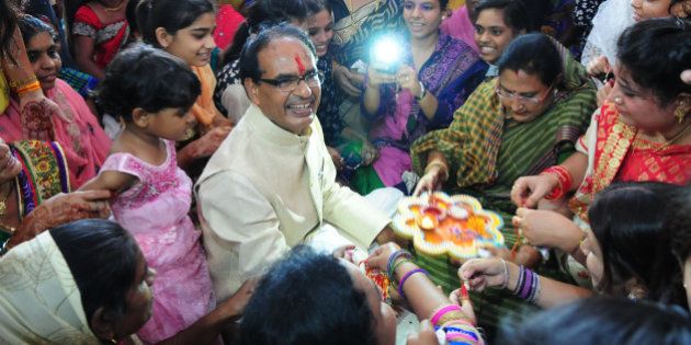 BHOPAL, INDIA - AUGUST 29: Women tying 'Rakhi' to the Madhya Pradesh Chief Minister Shivraj Singh Chouhan during a special Raksha Bandhan programme organised at CM house on August 29, 2015 in Bhopal, India. On Raksha Bandhan, sisters tie a rakhi (sacred thread) on her brother's wrist, which symbolizes the sister's love and prayers for her brother's well-being and the brother's lifelong vow to protect her. (Photo by Mujeeb Faruqui/Hindustan Times via Getty Images)
