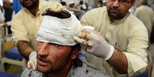 Pakistani paramedics treat a man injured in an earthquake at a hospital in Peshawar on October 26, 2015....