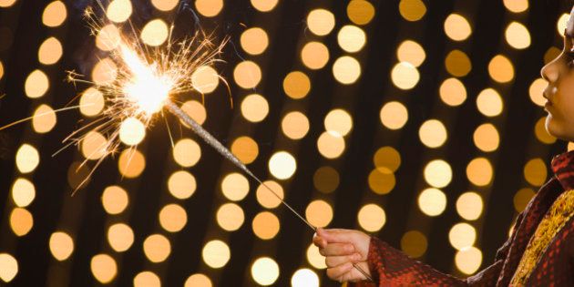 Boy (4-5) holding flashing sparkler during Diwali celebration