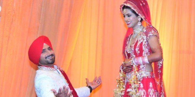 JALANDHAR, INDIA - OCTOBER 29: The newly wedded couple Indian cricketer Harbhajan Singh got on his knees with wide open arms like Bollywood actor Shah Rukh Khan for actress wife Geeta Basra posing for lensmen after getting married on October 29, 2015 at a resort on the outskirts of Jalandhar, India. Indian ace spinner Harbhajan, 35, and Geeta, who has acted in several Hindi and Punjabi films, have had a five years of courtship before they took the marital plunge. (Photo by Pardeep Pandit/Hindustan Times via Getty Images)