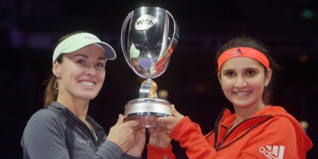 Martina Hingis of Switzerland, left, and Sania Mirza of India, right, pose with their trophy after they beat Carla Suarez Navarro and Garbine Muguruza, both of Spain during the doubles final at the WTA tennis finals in Singapore on Sunday, Nov. 1, 2015. (AP Photo/Joseph Nair)