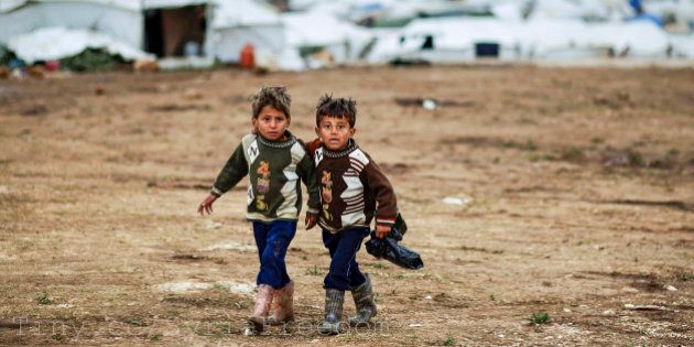 Syrian boys, whose family fled their home in Idlib, walk to their tent, at a camp for displaced Syrians, in the village of Atmeh, Syria, Monday, Dec. 10, 2012